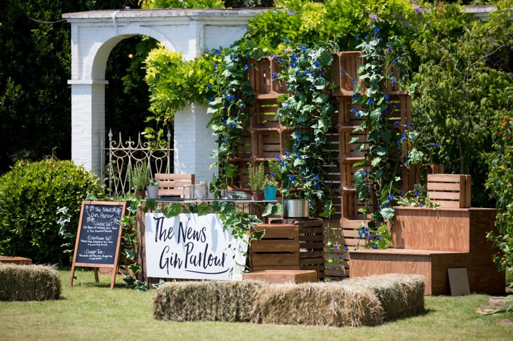 Custom build branded experience gin parlour with rustic hay-bale seating and greenery 