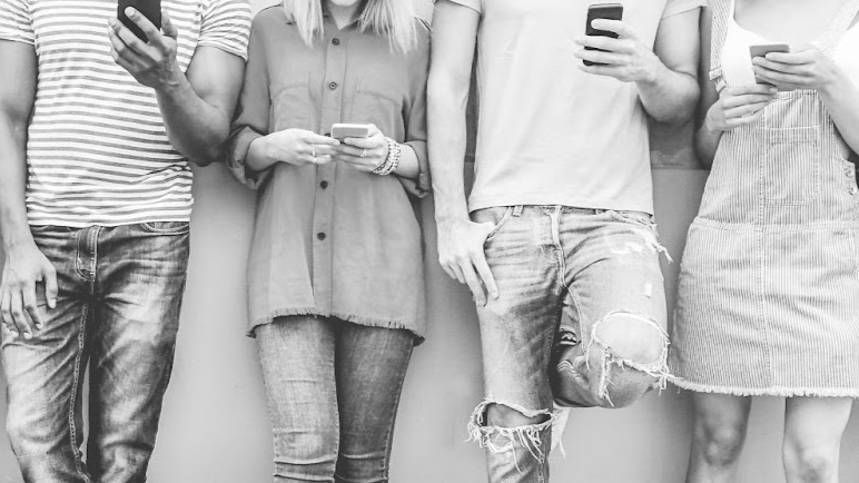 Line of people stand holding their mobile devices. Black and white photographh